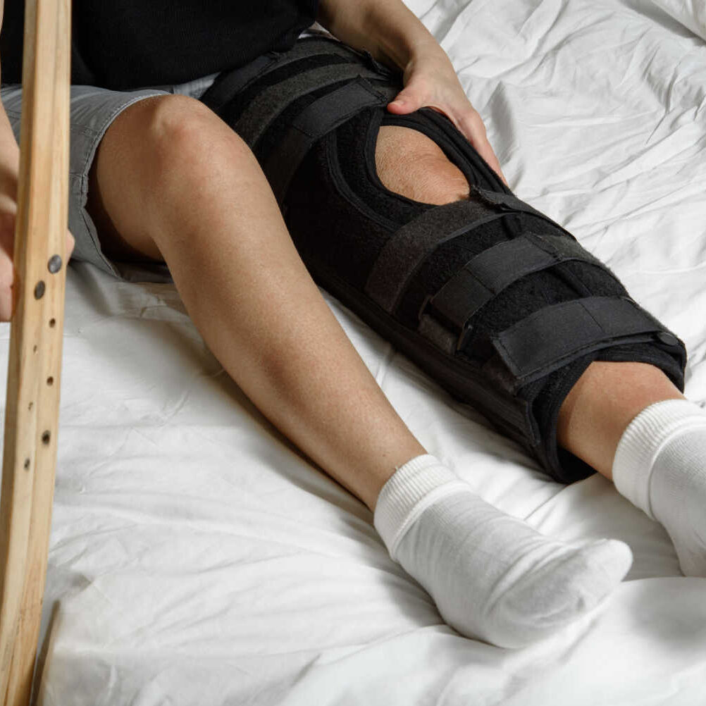 stock-photo-female-patient-wearing-orthosis-sitting-on-bed-holding-crutches-after-surgery-on-broken-leg-2107706447
