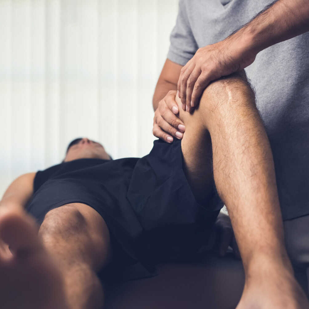 stock-photo-therapist-treating-injured-knee-of-athlete-male-patient-in-clinic-sport-physical-therapy-concept-688160710